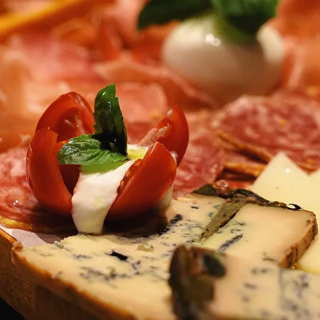 Fromages, charcuteries et tomates sur une planche chez Nino Fresco